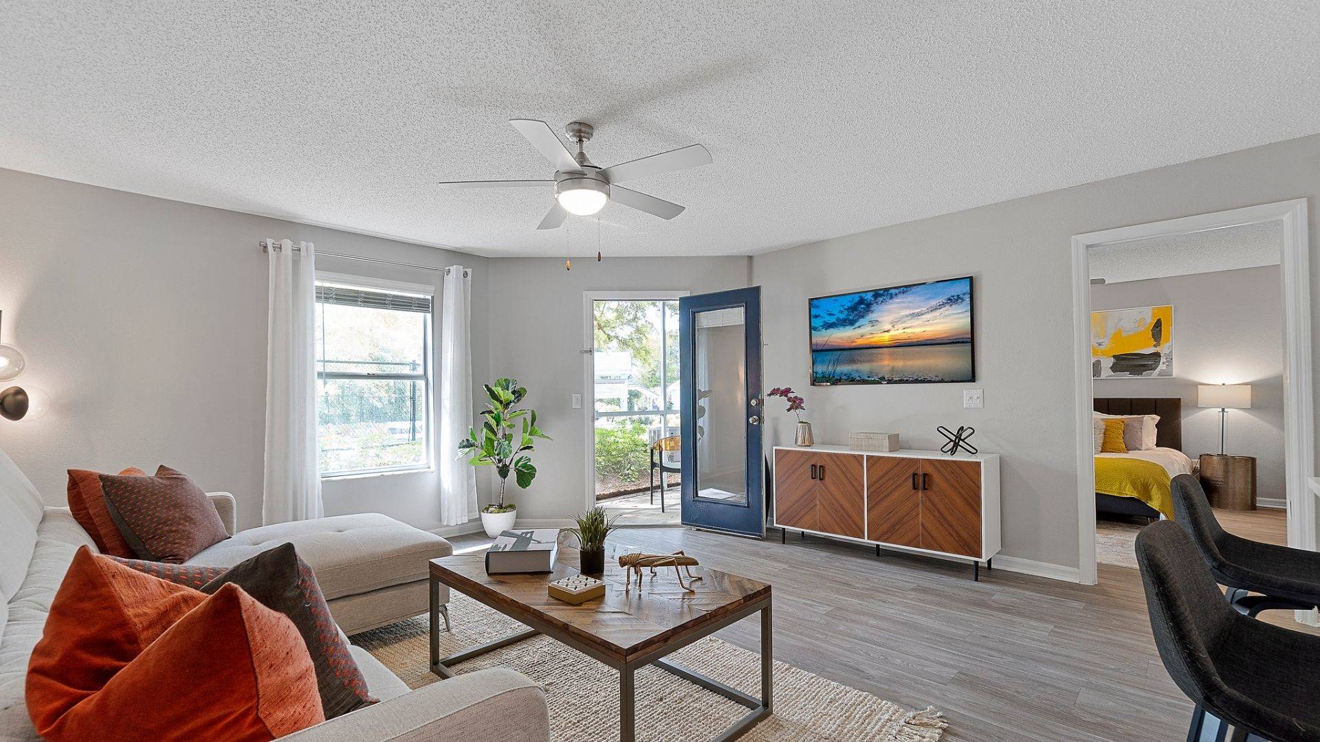 fully furnished living room leading to patios