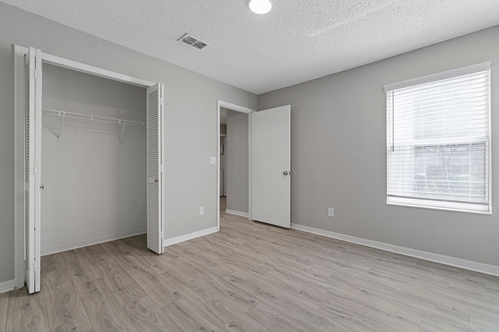 bedroom with window, closet and wood-style flooring